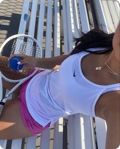 a woman holding a tennis racquet on top of a white bench