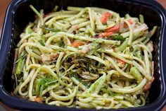 a black container filled with pasta and vegetables