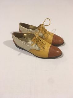 "vintage 1980s women's oxford shoes Escada, made in Italy 3 tone genuine leather brown toe/heel, yellow vamp/front sides, back sides ivory white yellow leather laces metallic gold insole leather sole w/back heel cap good vintage condition, light wear-see photos label size 8 1/2 B, see below measures, insole-9 3/4\" sole-10 3/8\" width-3 3/8\" heel-7/8\"     We do not offer returns or refunds unless something is grossly misrepresented. Please contact us within 2 business days of receiving to discuss any possible returns for this reason. We do not offer refunds for your shipping fees. Please feel free to contact us with any questions you may have about an item prior to purchase and we will gladly answer them." Yellow Wingtip Oxfords With Brogue Detailing, Retro Oxfords With Brogue Detailing And Round Toe, Retro Low-top Oxfords With Leather Sole, Retro Brogue Oxfords With Round Toe, Formal Yellow Oxfords With Round Toe, Retro Lace-up Oxfords With Leather Sole, Retro Leather Oxfords With Pointed Toe, Vintage Oxfords With Brogue Detailing For Spring, Retro Wingtip Oxfords For Fall