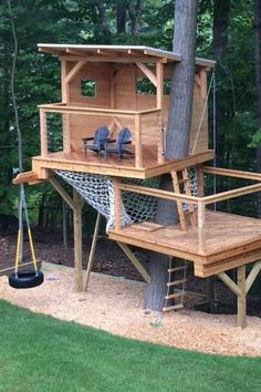 a tree house built into the side of a tree in a yard with two chairs and a hammock