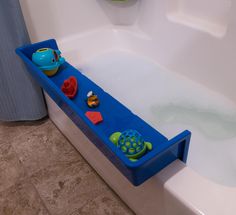 a bathtub filled with toys and water next to a blue towel dispenser