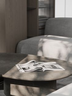 an open magazine sitting on top of a table next to a couch and coffee table