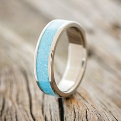 a wedding ring with blue and white sand inlays on the outside of it