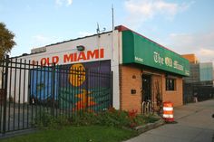 an old miami pizza restaurant is painted on the side of a brick building with a fence around it