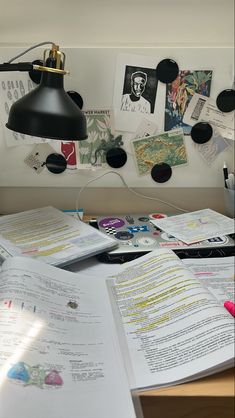 an open book sitting on top of a desk next to a lamp and other papers