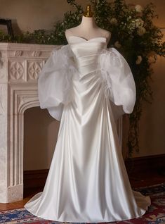 a white wedding dress on display in front of a fireplace