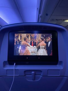 an airplane seat with a tv on it's side and some people in the background