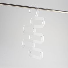 clear glass letters hanging from a metal bar on a white wall with a silver pole in the background