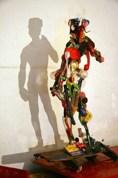 the shadow of a man standing next to a pile of assorted items in front of a white wall