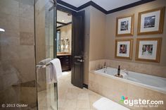 a bathroom with a walk in shower next to a bathtub and sink under pictures on the wall