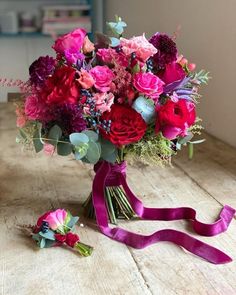 a bouquet of flowers is sitting on the table next to a purple ribbon and scissors