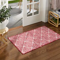 a red and white rug sitting on top of a wooden floor next to a door