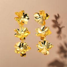 Introduce a touch of vintage charm to your look with our Golden Petal Earrings. These elegant drop earrings feature a trio of delicate flowers, meticulously crafted to bring a whimsical yet sophisticated accent to your attire. The golden hue adds a warm glow, making these earrings a versatile addition to both casual and formal outfits. Key Features: - Vintage Floral Design: Three-dimensional petals create a blooming bouquet that dangles gracefully. - Golden Finish: The earrings are plated in a rich gold tone for an opulent look. - Lightweight and Comfortable: Designed for all-day wear without compromising style. - Versatile Accessory: Perfect for adding a pop of vintage flair to any ensemble. - Ideal Gifting: A beautiful choice for gifting on special occasions or as a self-treat. Ordering Blooming Bouquet, Petal Earrings, Earrings Golden, Vintage Floral Design, Formal Outfits, Delicate Flowers, Delicate Flower, Floral Vintage, Formal Outfit