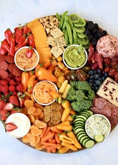 a platter filled with different types of fruits, vegetables and dips on top of each other