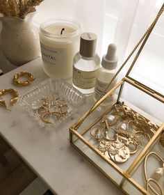 a table topped with lots of gold jewelry and bottles filled with lotion sitting on top of it