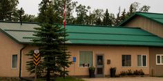 a building with a green roof and trees in the background