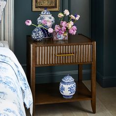 a wooden table topped with blue and white vases next to a painting on the wall