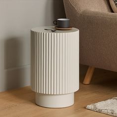 a white table with a cup on it next to a couch