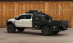 a white truck parked in front of a wooden building with two garage doors behind it