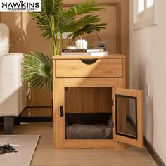 a dog bed in a wooden cabinet next to a potted plant and white couch