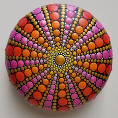 an artistically painted rock with orange, pink and yellow dots on it's surface