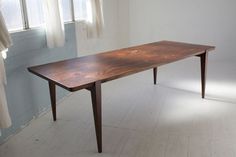 a wooden table sitting in the middle of a room with white walls and flooring