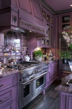 a kitchen with purple cabinets and stainless steel stove top oven, vases on the counter