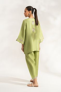 Siran (B) reinterprets the classic shalwar kameez with its box cut front open pure rawsilk shirt in a sage green hue. The subtle combination of ivory, lavender, and lilac embroidery elevates the shirt and the hem of the pure rawsilk shalwar.Model Height: 5'6 Length: 29" Green Silk Kurta With Embroidered Border, Green Palazzo Set With Embroidered Border For Eid, Green Palazzo Set With Embroidered Border For Wedding, Wedding Green Palazzo Set With Embroidered Border, Pista Green Long Sleeve Silk Kurta, Elegant Pista Green Sets With Embroidered Border, Pista Green Silk Kurta For Spring, Formal Green Kurta With Chikankari Embroidery, Elegant Green Kurta With Embroidered Border