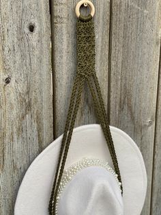 a white hat hanging on the side of a wooden fence next to a string with beads