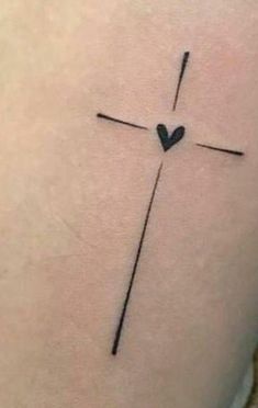 a cross tattoo on the back of a woman's stomach with a heart in it