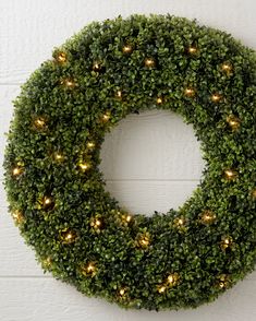 a green wreath with lights hanging on the wall