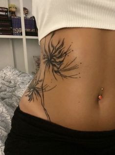 a woman's stomach with a tattoo on her side and flowers in the middle