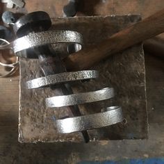 a metal object sitting on top of a table next to a hammer and some nails