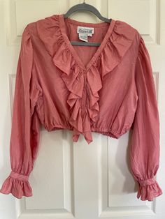 Vintage 90s 100% silk pink blouse by Christie & Jill.  Cropped fit, button front, ruffles at neck, down the front, and at wrists.  Waist elastic is very stretchy.  Has a few small marks on left shoulder and near cuff, see last 2 pictures. Pinhole near back hem and another near right side hem, does not like they will get any bigger.  See video for close up. Vintage size M.  Best for modern size M.  Be sure to check measurements and compare to a similar garment in your closet. Length 17" Shoulders 16.75" PTP 20.75" (41.5 chest) Waist 11.75" unstretched (23.5) Sleeve length 24" At this time standard shipping is a flat fee to the United States only.  Additional items ship for only one dollar.  To place an order to outside the US, please send me a message and I will reserve a listing for you wi One Dollar, Womens Blouses, Pink Blouse, Pink Silk, Ruffle Top, Austin Tx, Right Side, Womens Clothing Tops, Send Me