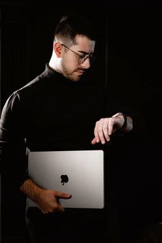 a man in black shirt holding an apple laptop