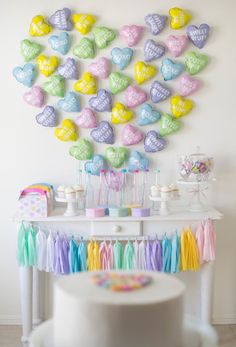 a white table topped with lots of candy hearts on top of it's wall