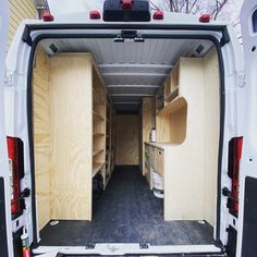 the back end of a white van with wooden shelves