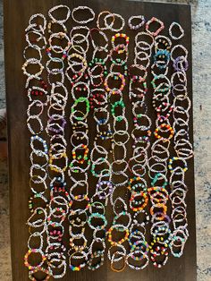 a bunch of bracelets that are sitting on a wooden board with beads all over them