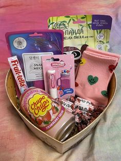 a basket filled with lots of different items on top of a bed next to a pink blanket