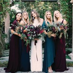 a group of women standing next to each other in front of a gazebo holding bouquets