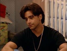 a young man sitting at a table in front of a baby crib and looking down