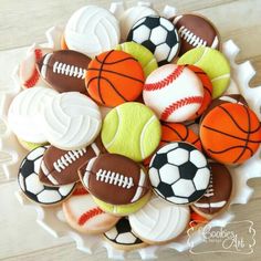 decorated cookies in the shape of sports balls and basketballs on a white platter