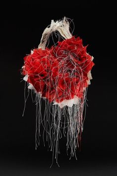 a red and white flower arrangement on a black background with some branches sticking out of it