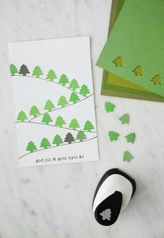 a pair of scissors and some cards on a table with paper cut out to look like trees