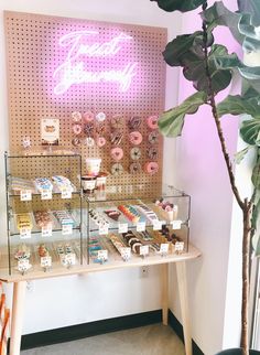 a display case with donuts and other pastries on it next to a potted plant