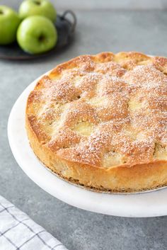 a cake sitting on top of a white plate covered in powdered sugar next to an apple