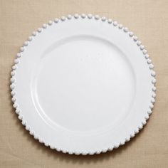 a white plate with beaded edges on a beige surface, top view from above