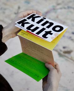 a person holding up a book with the word kino kultt on it