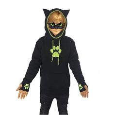 a child wearing a black cat costume with green paw prints on it's chest