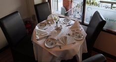 the table is set with silverware and white linens for two people to eat